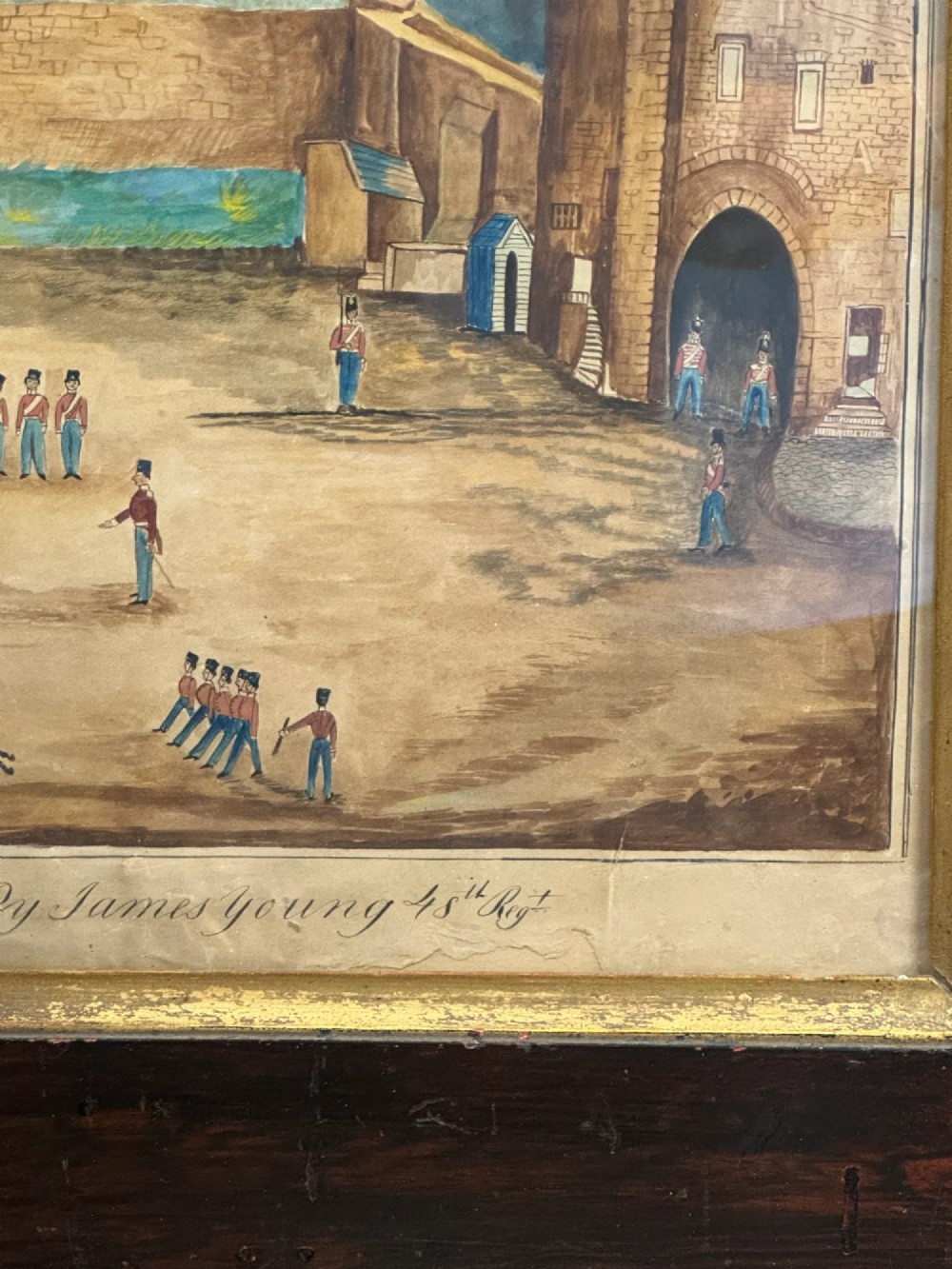 An antique framed watercolour painting depicting soldiers assembled in a castle courtyard within a wide dark wooden frame. View II