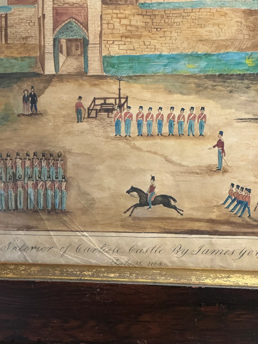 An antique framed watercolour painting depicting soldiers assembled in a castle courtyard within a wide dark wooden frame. View III