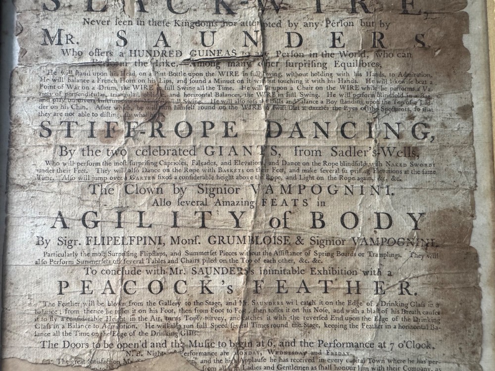 An 18th-century paper handbill with black letterpress typography advertising performance acts, displayed in a black frame with a gilt inner border. View IV