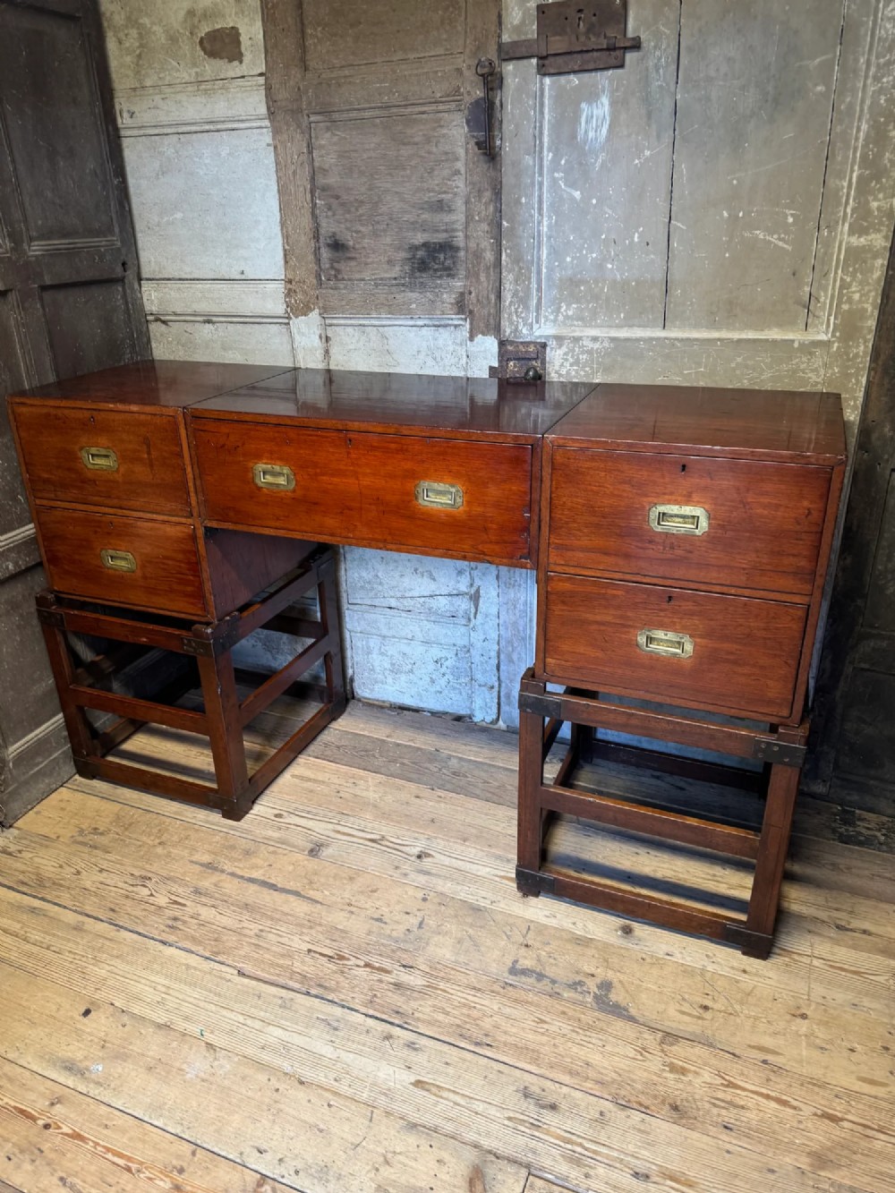 Late 19th-century Anglo-Indian campaign desk crafted from rich reddish-brown timber with flush brass handles and open frame bases.