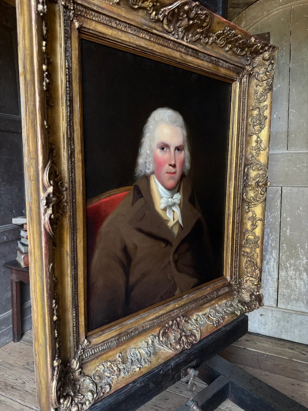 An 18th-century oil painting on canvas depicting a gentleman in a brown coat and white cravat, housed in a thick, ornate gilded frame. View II