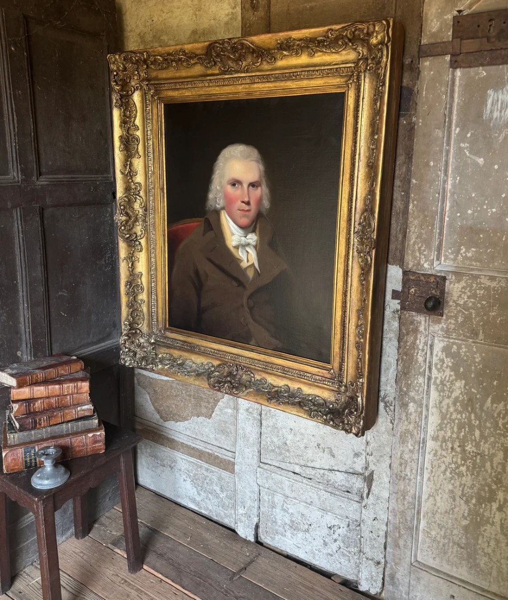 An 18th-century oil painting on canvas depicting a gentleman in a brown coat and white cravat, housed in a thick, ornate gilded frame. View III