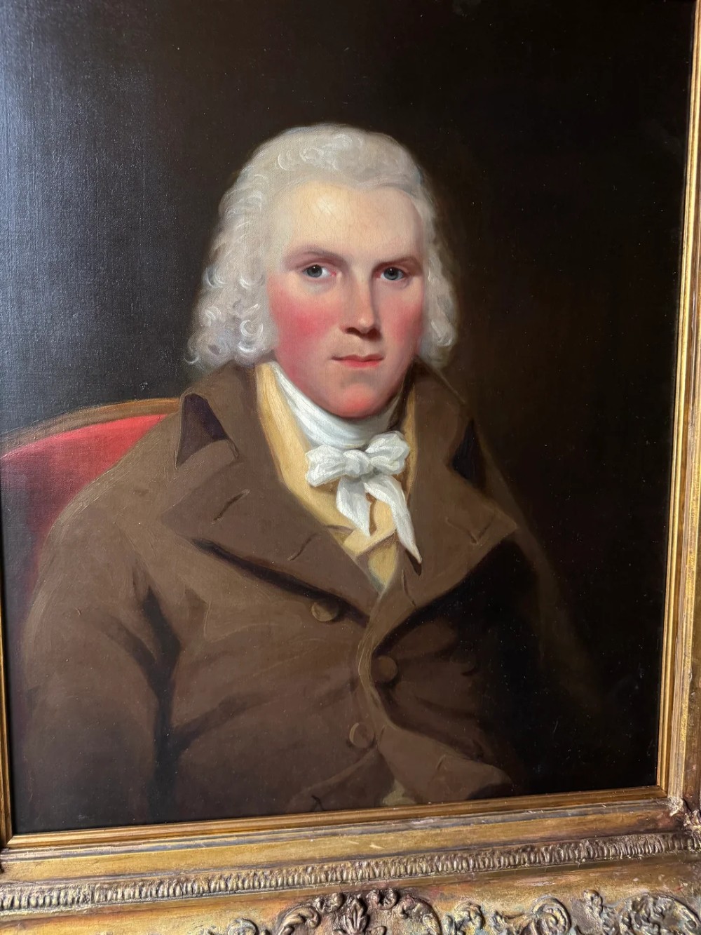 An 18th-century oil painting on canvas depicting a gentleman in a brown coat and white cravat, housed in a thick, ornate gilded frame. View VI