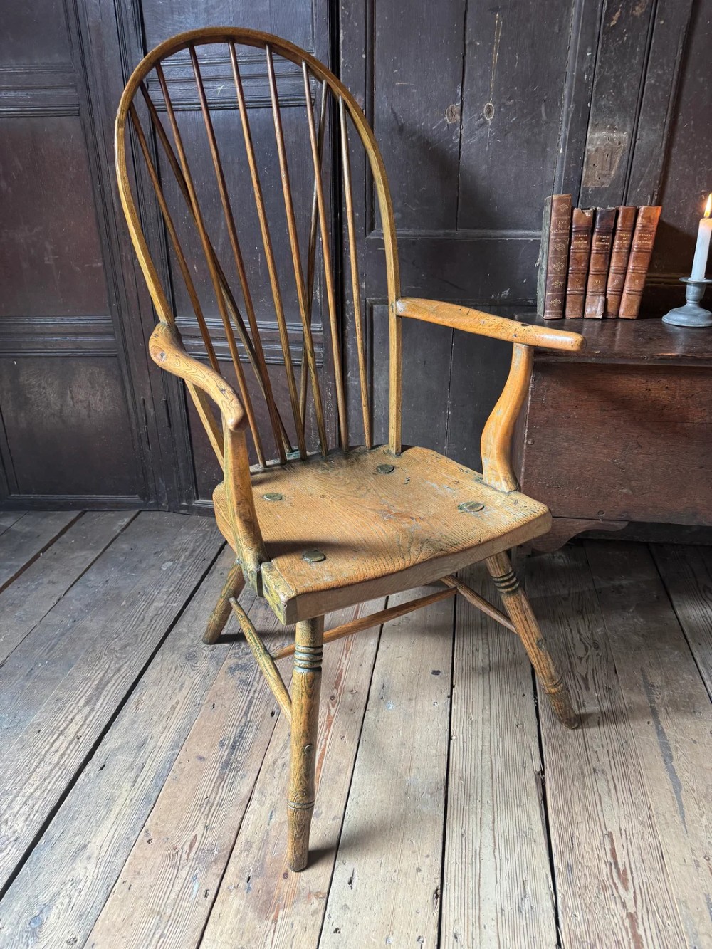 A George III high hoop-back Windsor armchair crafted from elm and ash with turned legs and a carved timber seat.