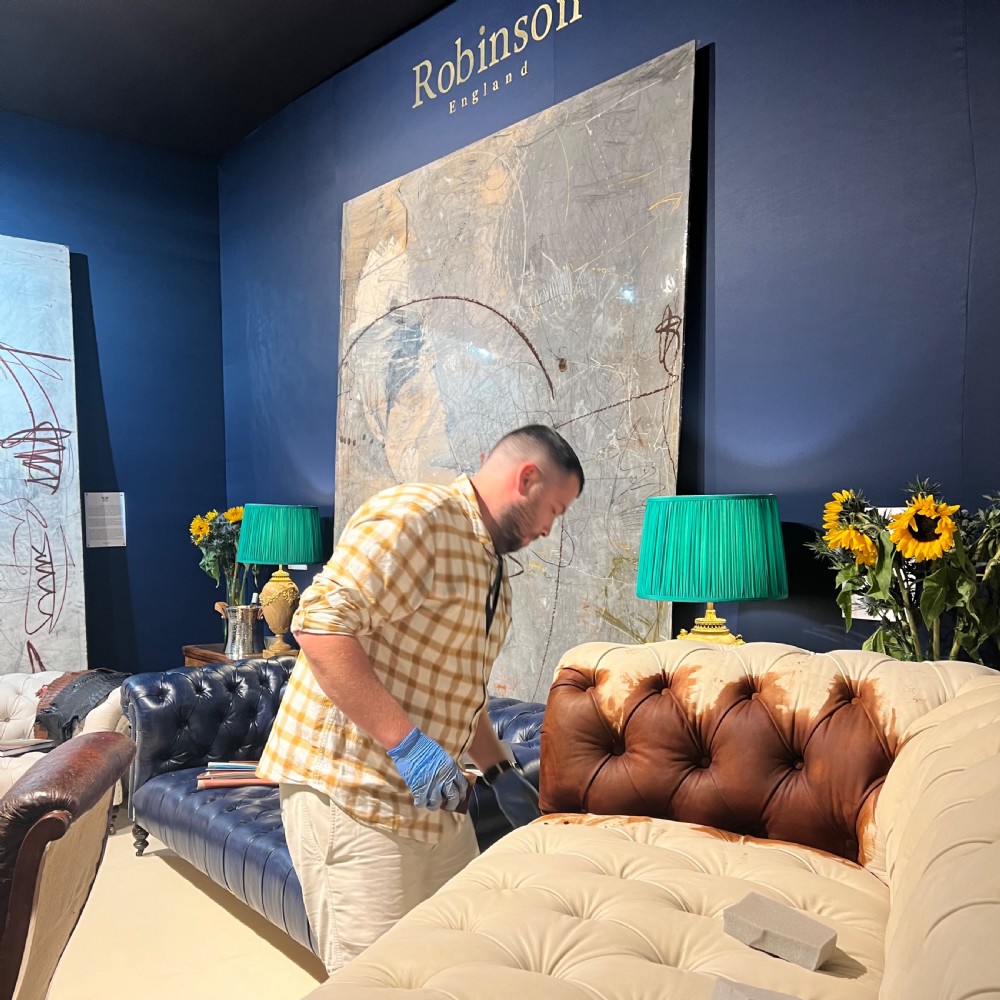A 19th-century brown hand-dyed leather Chesterfield sofa featuring deep button tufting, rolled arms, and reeded wooden legs on brass castors. View V