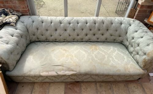 fig 1. A large antique Chesterfield sofa featuring deep buttoned pale blue damask fabric upholstery, rolled arms, and turned wooden feet.