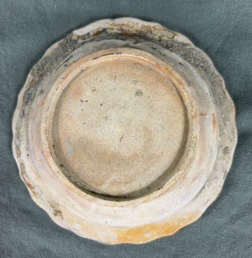 fig 3. A circular off-white antique ceramic dish featuring a scalloped rim, central meander pattern, and subtle marine mineral deposits.