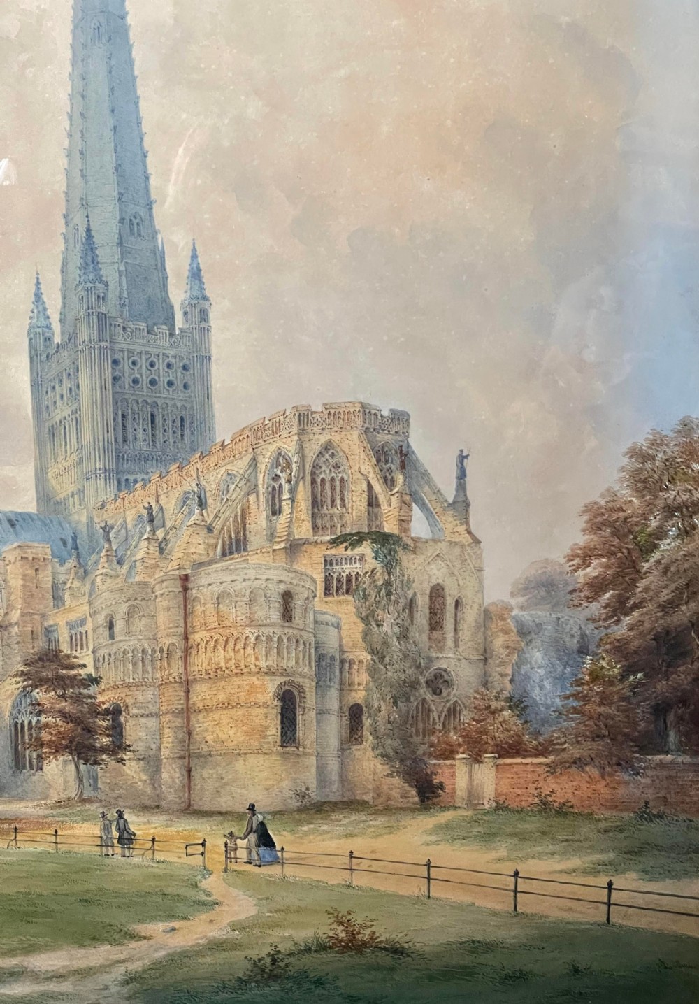 A nineteenth-century watercolour painting depicting Norwich Cathedral with a detailed spire, flying buttresses, and figures on the surrounding lawn. View V