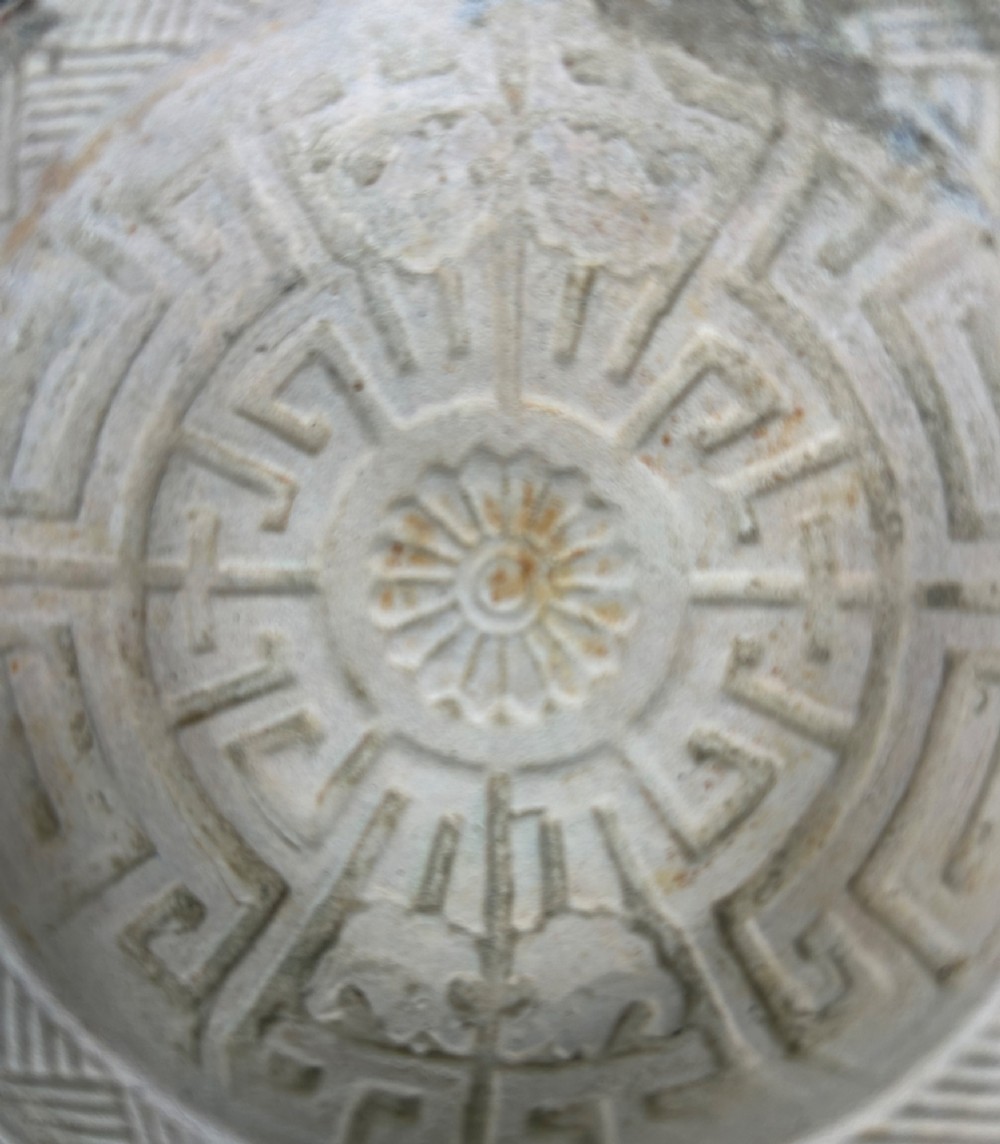 A circular off-white antique ceramic dish featuring a scalloped rim, central meander pattern, and subtle marine mineral deposits. View III