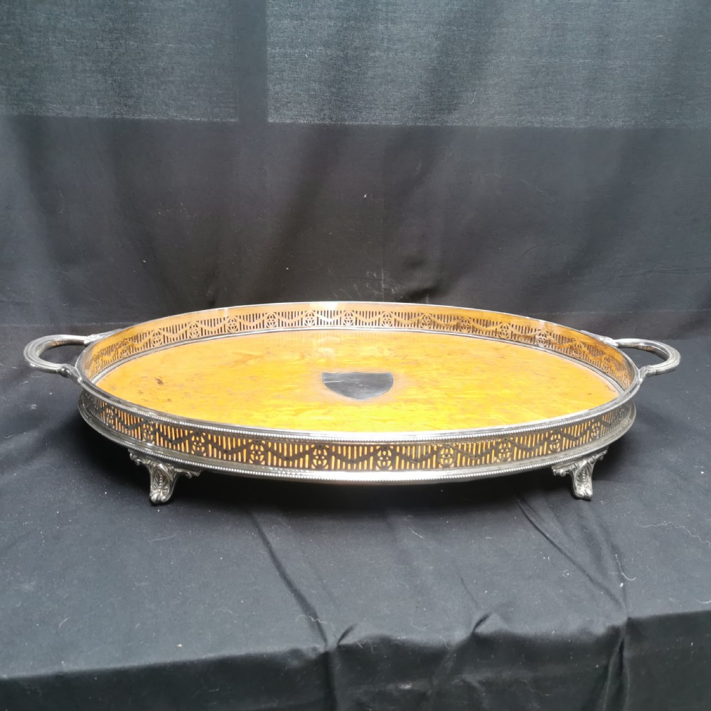 An oval antique oak serving tray with a silver-plated pierced gallery rim, twin handles, and an unengraved shield cartouche in the centre. View II