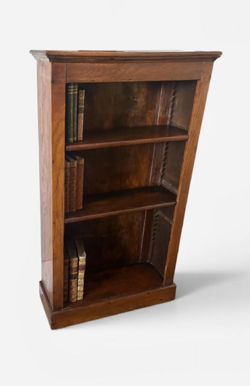 A narrow Edwardian oak open bookcase featuring adjustable wooden shelves and a simple plinth base. View II