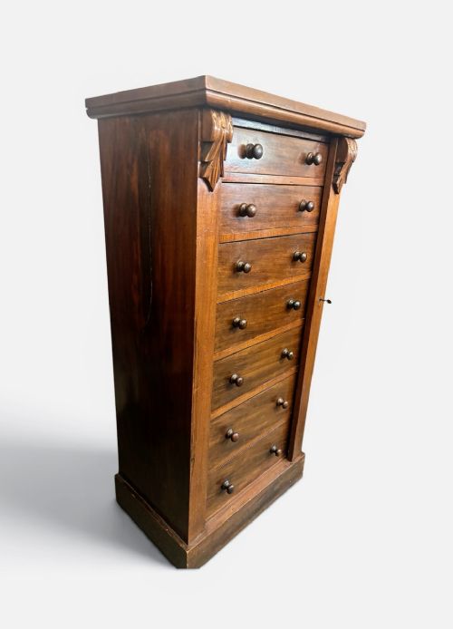 A tall Victorian walnut Wellington chest featuring seven stacked drawers, a right-hand locking stile, carved corner corbels, and turned wooden handles on a plinth base. View IV