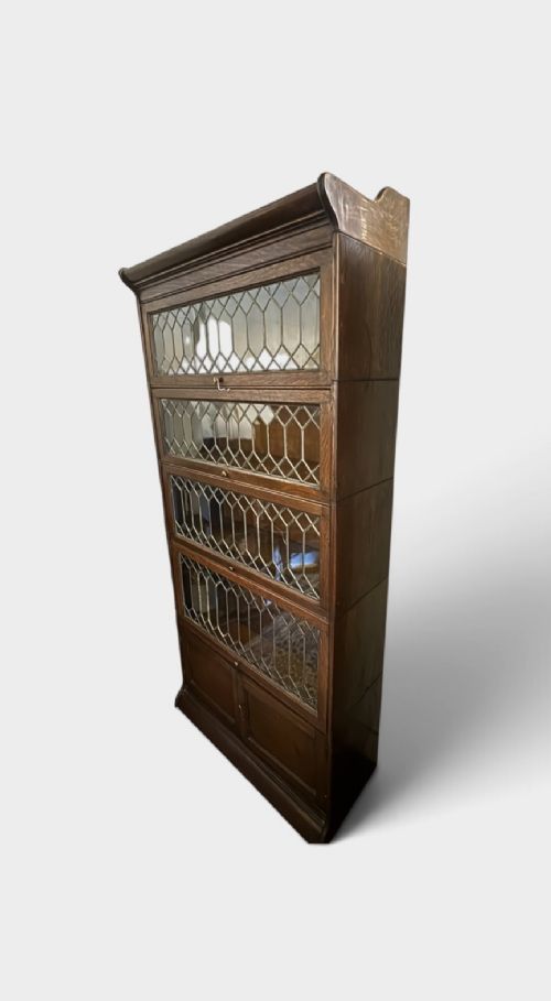 An early twentieth-century dark oak sectional barrister bookcase featuring four leaded glass door tiers above a two-door panelled cabinet base. View II