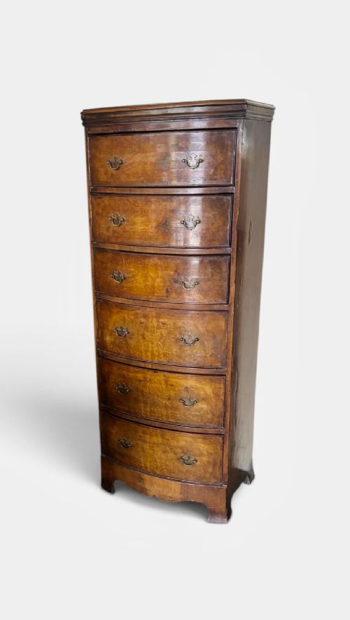 An early 20th-century figured walnut bow-front tallboy featuring six stacked drawers with brass bail handles and bracket feet. View III