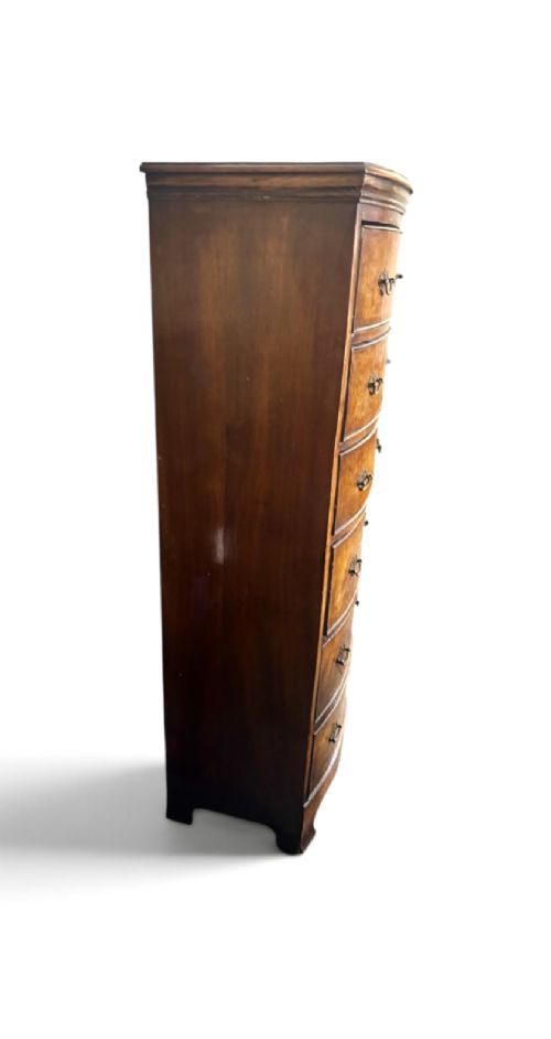 An early 20th-century figured walnut bow-front tallboy featuring six stacked drawers with brass bail handles and bracket feet. View V