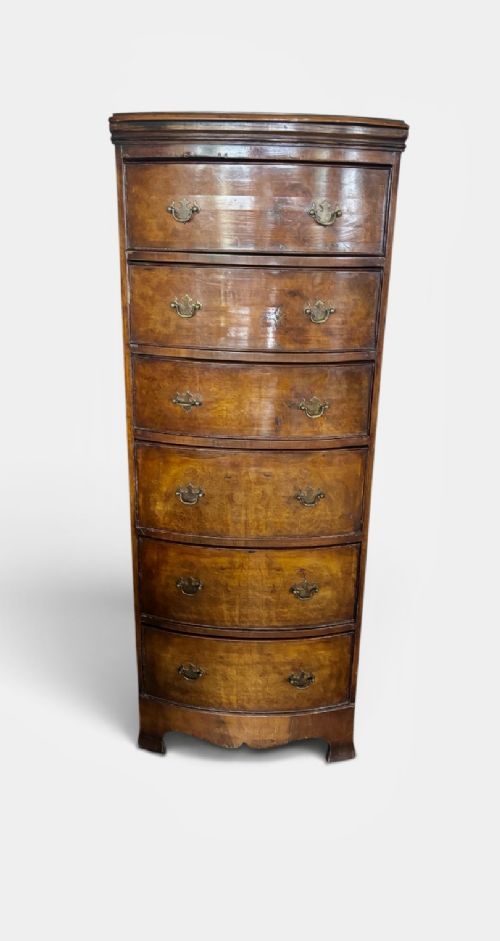 An early 20th-century figured walnut bow-front tallboy featuring six stacked drawers with brass bail handles and bracket feet. View VI