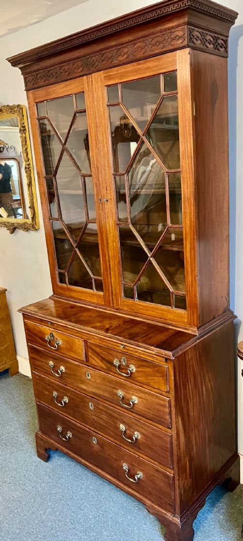 A George III mahogany library bookcase featuring astragal glazed upper doors above a chest of four drawers with brass swan-neck handles. View II