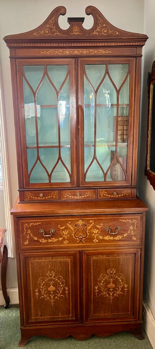 An Edwardian mahogany secretaire bookcase featuring satinwood marquetry inlays, a swan-neck pediment, glazed upper doors, and a pull-out desk drawer above lower cupboards. View II