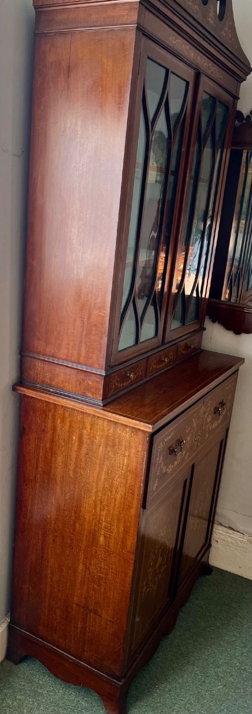 An Edwardian mahogany secretaire bookcase featuring satinwood marquetry inlays, a swan-neck pediment, glazed upper doors, and a pull-out desk drawer above lower cupboards. View VII