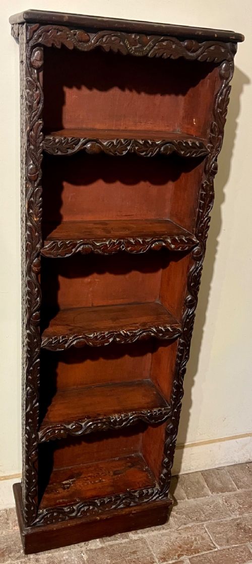 A tall, narrow Victorian open bookcase made of dark carved oak and pine with five shelves decorated with leaf borders. View III