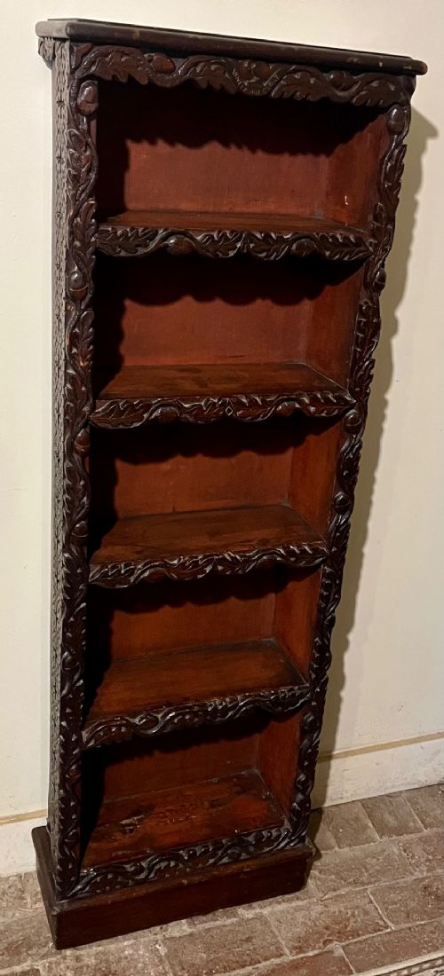 A tall, narrow Victorian open bookcase made of dark carved oak and pine with five shelves decorated with leaf borders. View IV