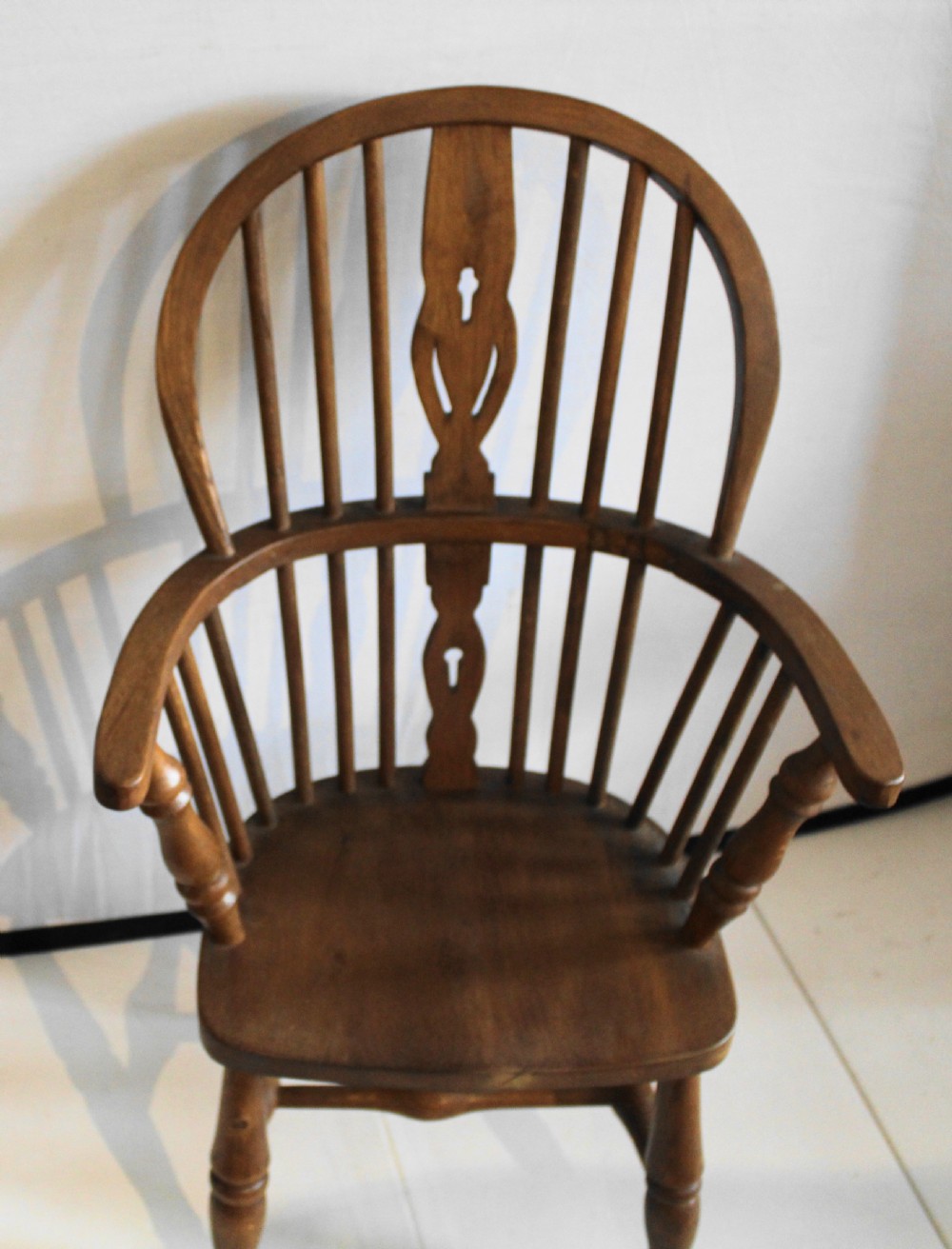 A child-sized oak Windsor armchair featuring a hoop back, pierced central splat, turned legs, and curved armrests. View II