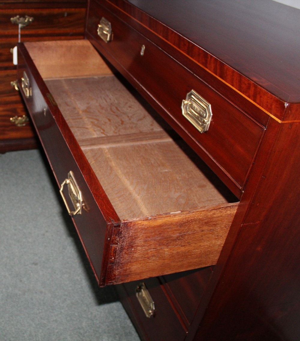 A Regency figured mahogany chest of four graduated drawers featuring brass handles and splayed bracket feet. View VII