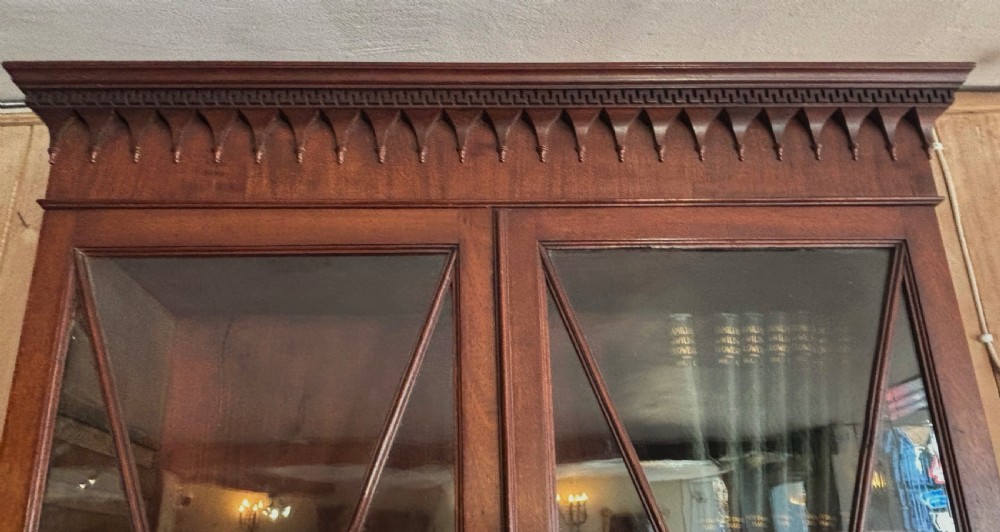 A Regency mahogany secretaire bookcase featuring glazed double doors with geometric astragal glazing above a chest of drawers with brass ring handles. View VII