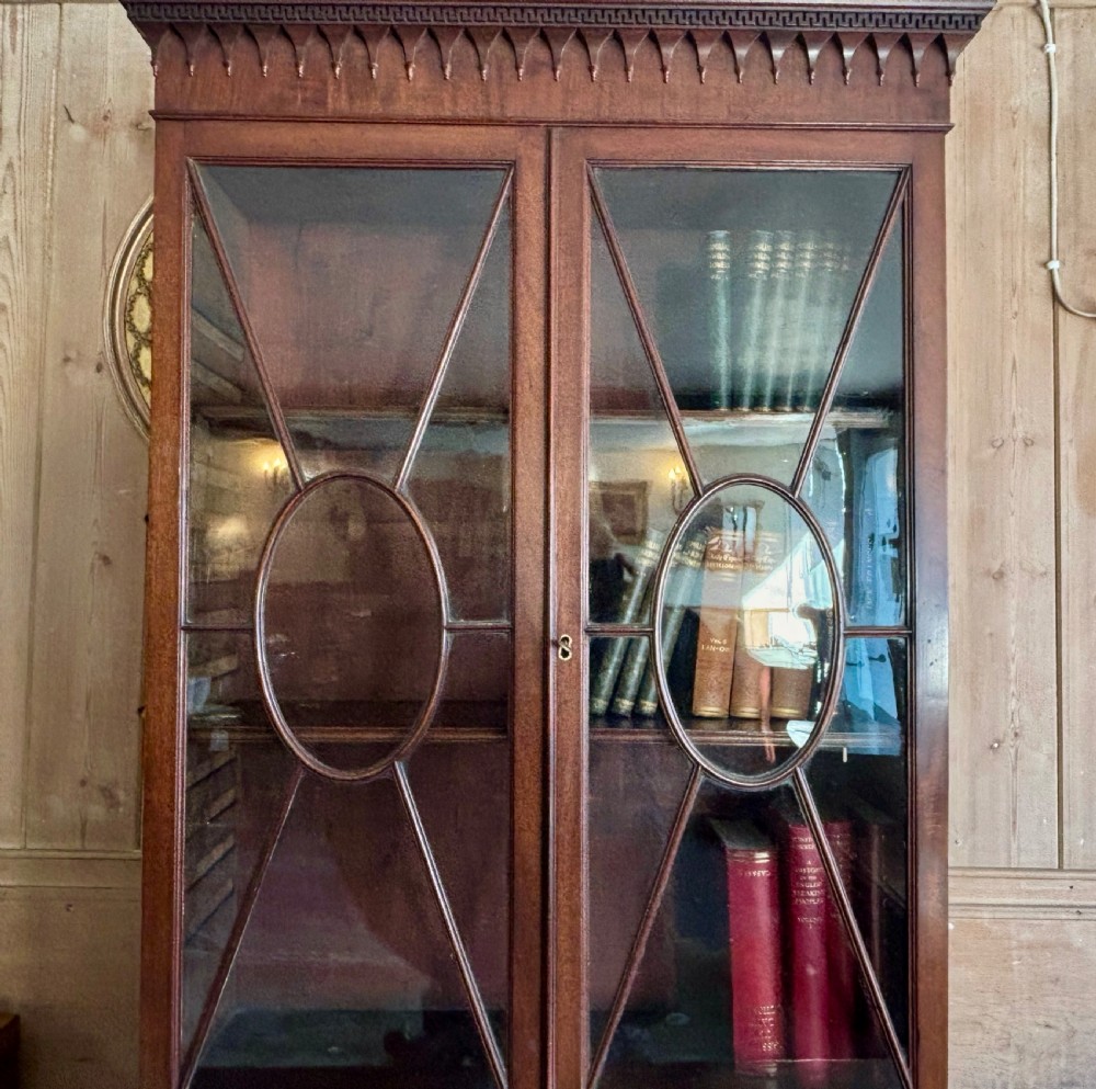 A Regency mahogany secretaire bookcase featuring glazed double doors with geometric astragal glazing above a chest of drawers with brass ring handles. View VIII