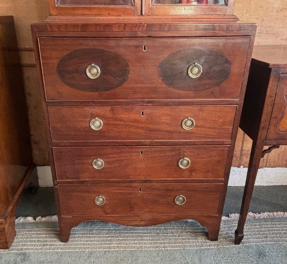 A Regency mahogany secretaire bookcase featuring glazed double doors with geometric astragal glazing above a chest of drawers with brass ring handles. View X