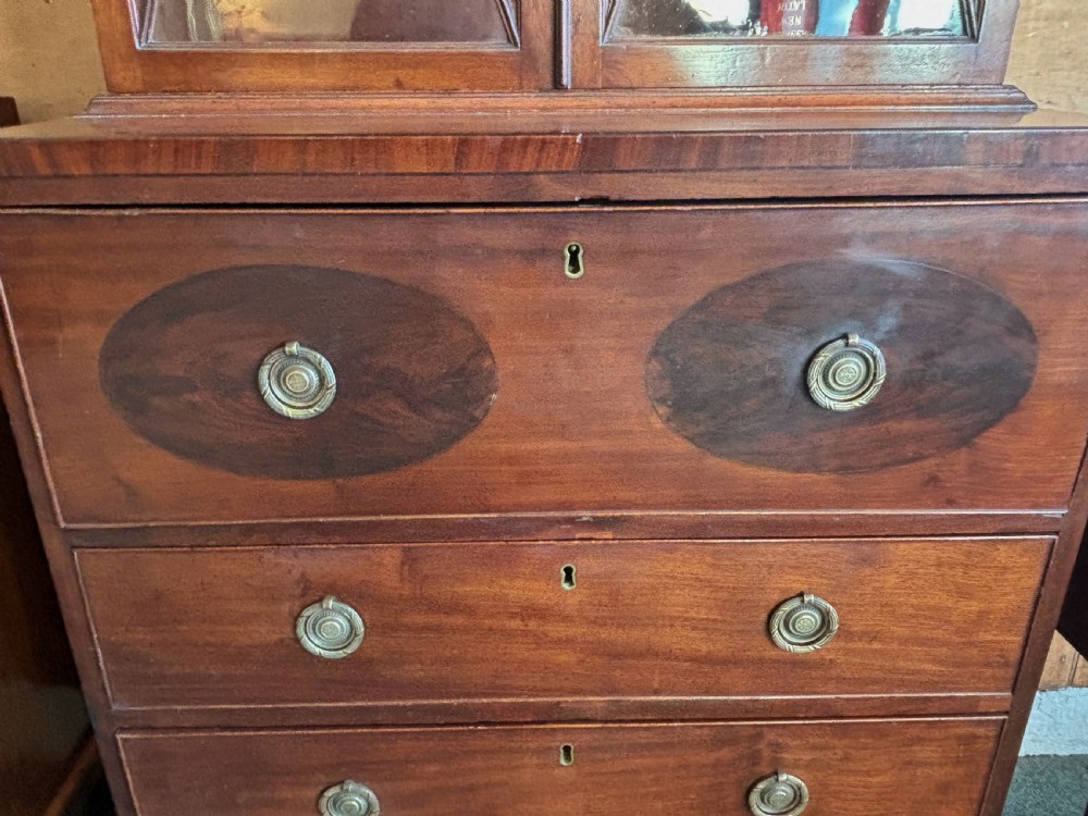 A Regency mahogany secretaire bookcase featuring glazed double doors with geometric astragal glazing above a chest of drawers with brass ring handles. View XI