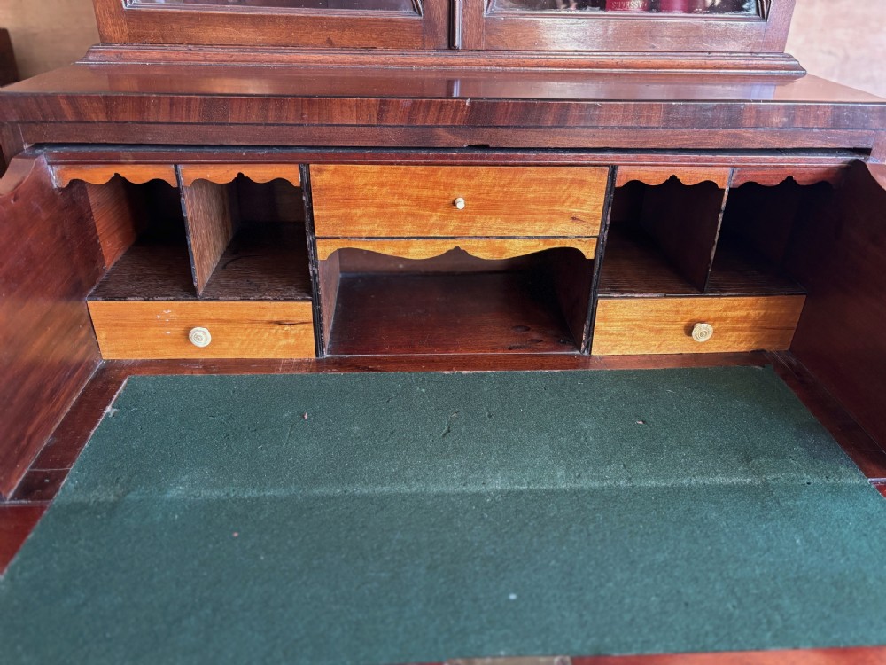 A Regency mahogany secretaire bookcase featuring glazed double doors with geometric astragal glazing above a chest of drawers with brass ring handles. View XIV