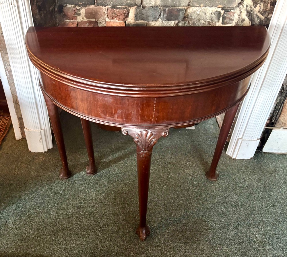 A George III mahogany demi-lune card table with carved shell knees and cabriole legs. View V
