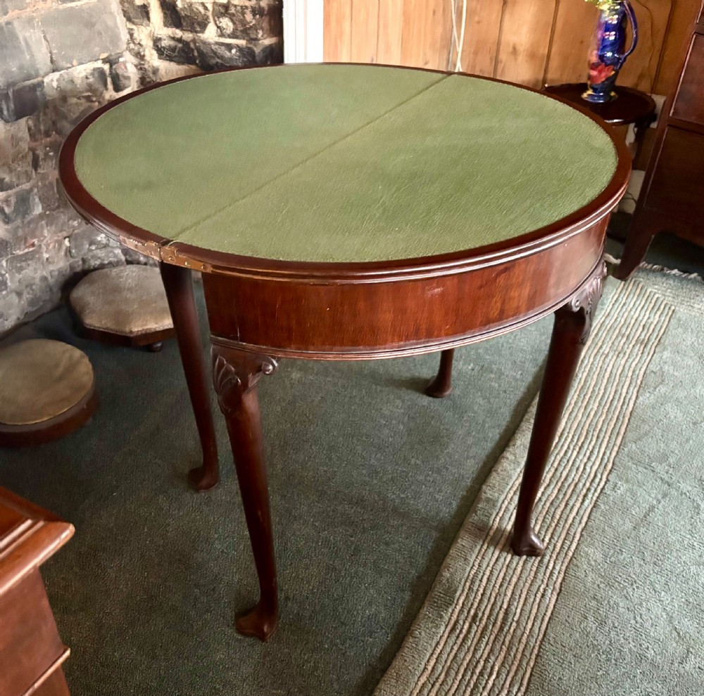A George III mahogany demi-lune card table with carved shell knees and cabriole legs. View VIII