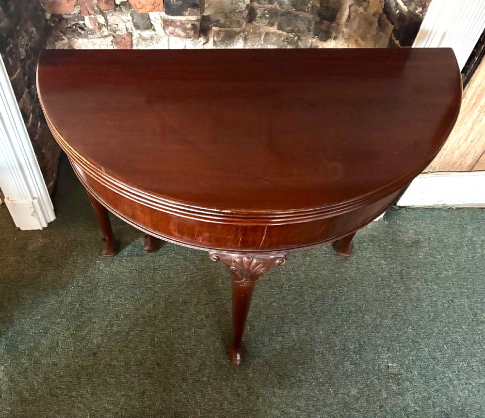A George III mahogany demi-lune card table with carved shell knees and cabriole legs. View IX