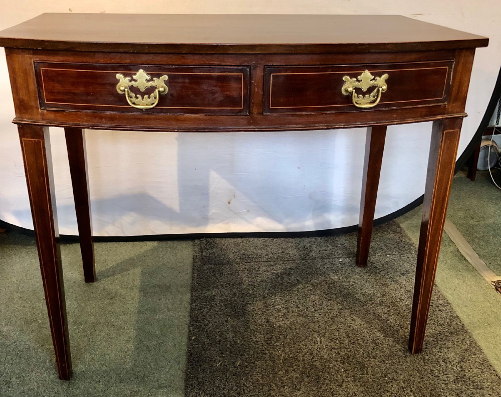 A nineteenth-century mahogany bow-fronted side table featuring two crossbanded drawers with brass handles and tapered legs. View III