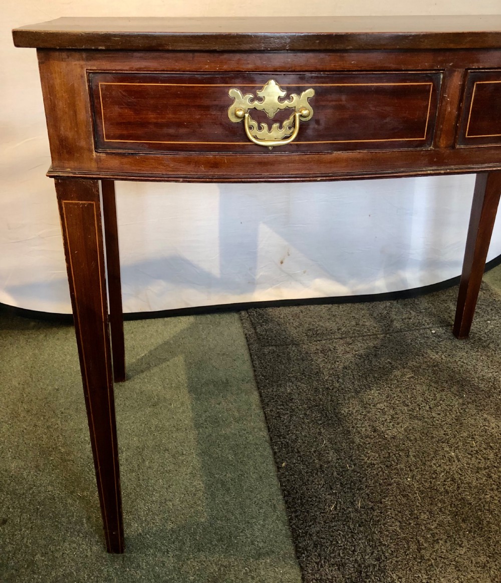 A nineteenth-century mahogany bow-fronted side table featuring two crossbanded drawers with brass handles and tapered legs. View IV