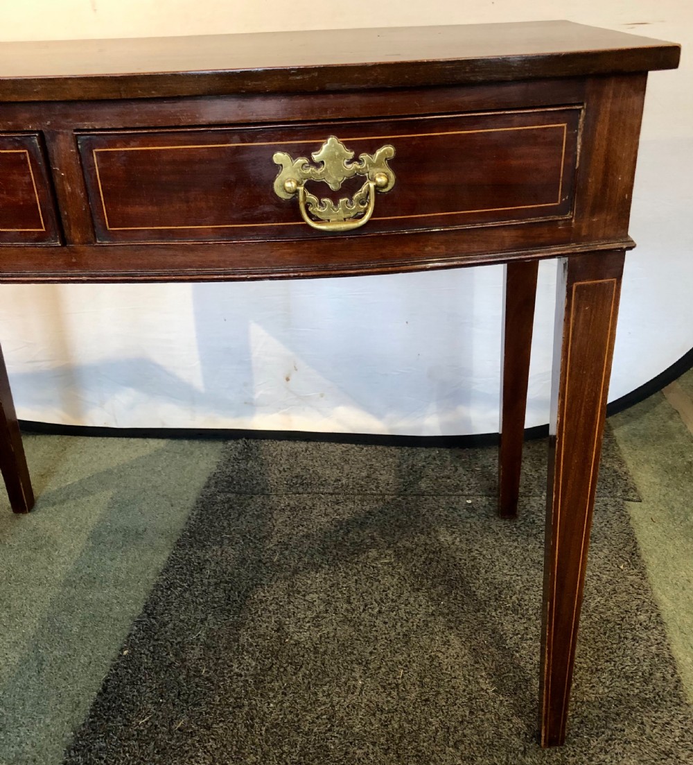 A nineteenth-century mahogany bow-fronted side table featuring two crossbanded drawers with brass handles and tapered legs. View V
