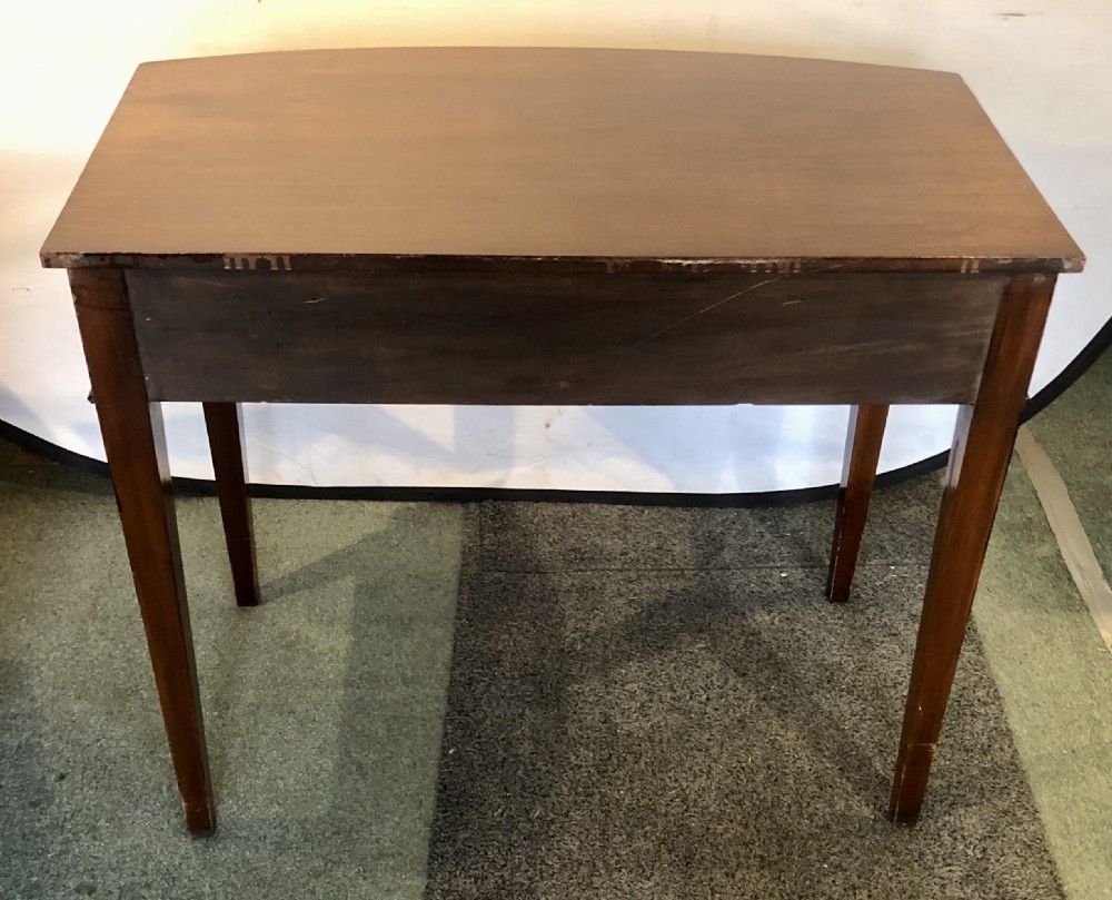 A nineteenth-century mahogany bow-fronted side table featuring two crossbanded drawers with brass handles and tapered legs. View X