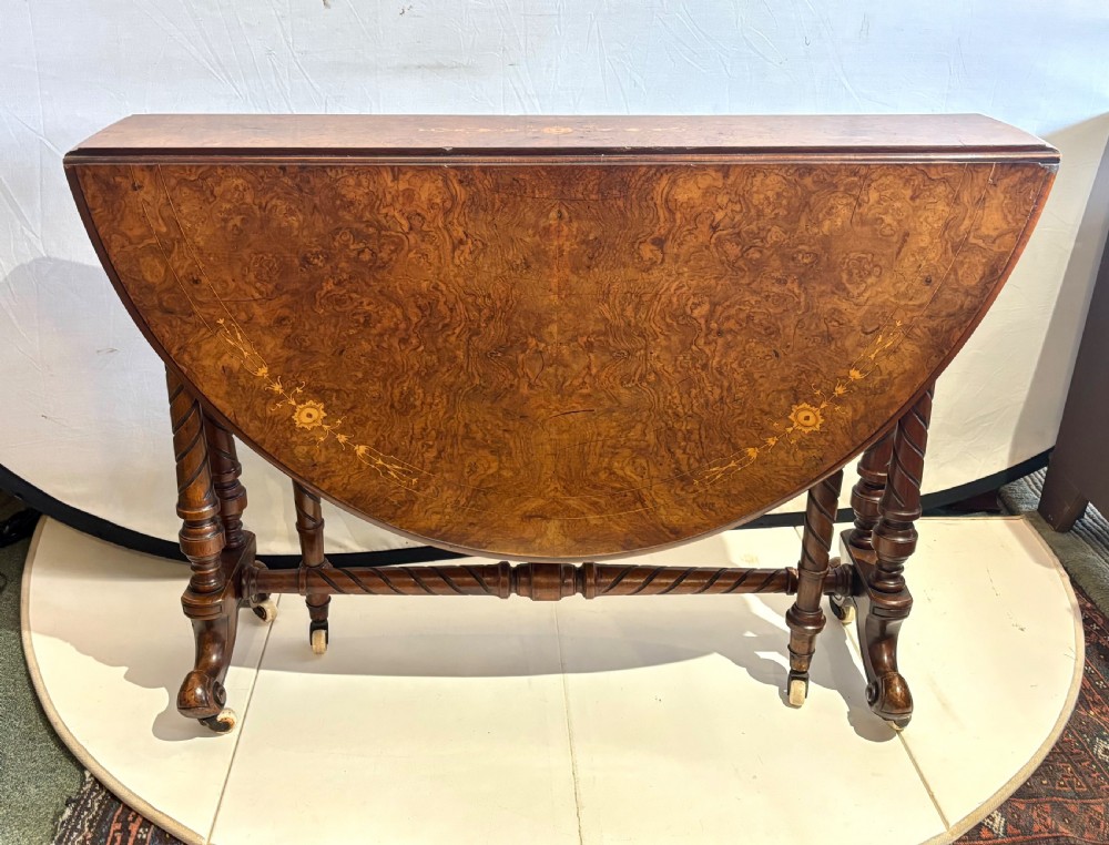 A Victorian burr walnut oval Sutherland table with detailed floral marquetry inlays, turned legs, and drop leaves extended. View III