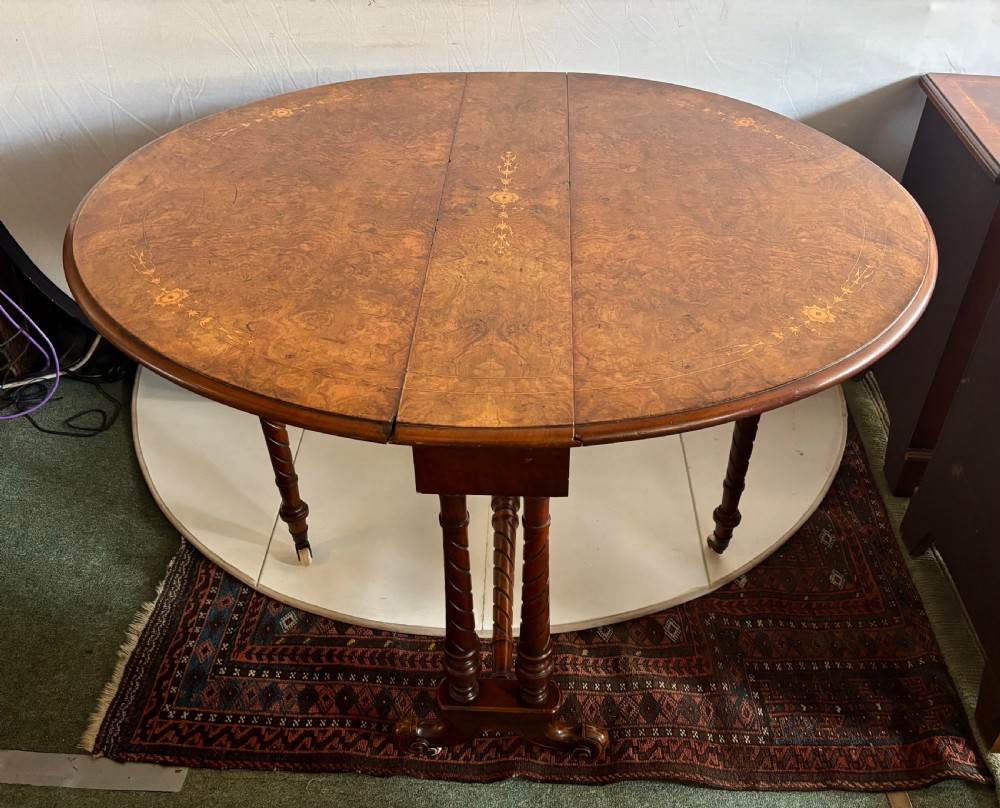 A Victorian burr walnut oval Sutherland table with detailed floral marquetry inlays, turned legs, and drop leaves extended. View VIII
