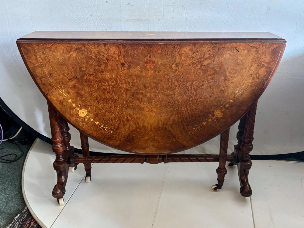 A Victorian burr walnut oval Sutherland table with detailed floral marquetry inlays, turned legs, and drop leaves extended. View IX
