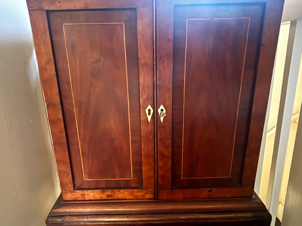 A small 19th-century mahogany cabinet featuring two open outer doors displaying four inlaid drawers with floral brass handles, supported on cabriole legs. View V