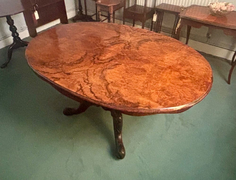 An oval Victorian breakfast table made of polished figured walnut veneer with a central carved pedestal base and splayed legs. View IV