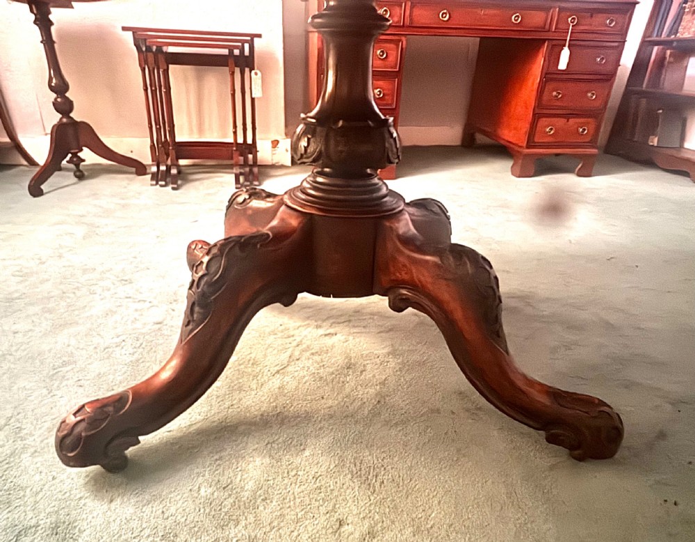 An oval Victorian breakfast table made of polished figured walnut veneer with a central carved pedestal base and splayed legs. View VI