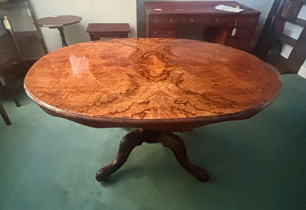An oval Victorian breakfast table made of polished figured walnut veneer with a central carved pedestal base and splayed legs. View VII