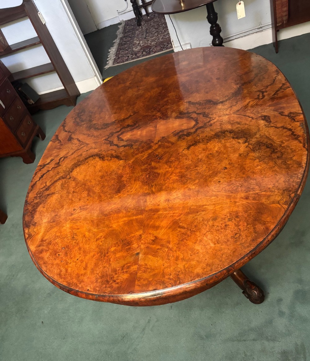 An oval Victorian breakfast table made of polished figured walnut veneer with a central carved pedestal base and splayed legs. View VIII