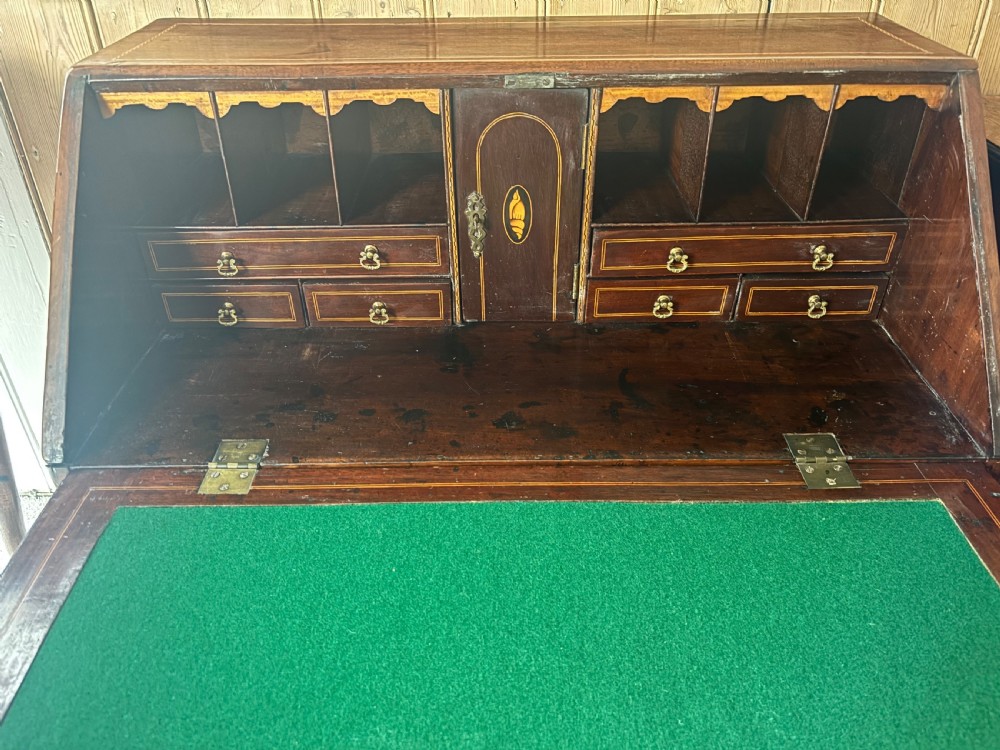 An 18th-century George III mahogany slant-front bureau featuring satinwood shell inlays and four graduating drawers with brass handles. View III