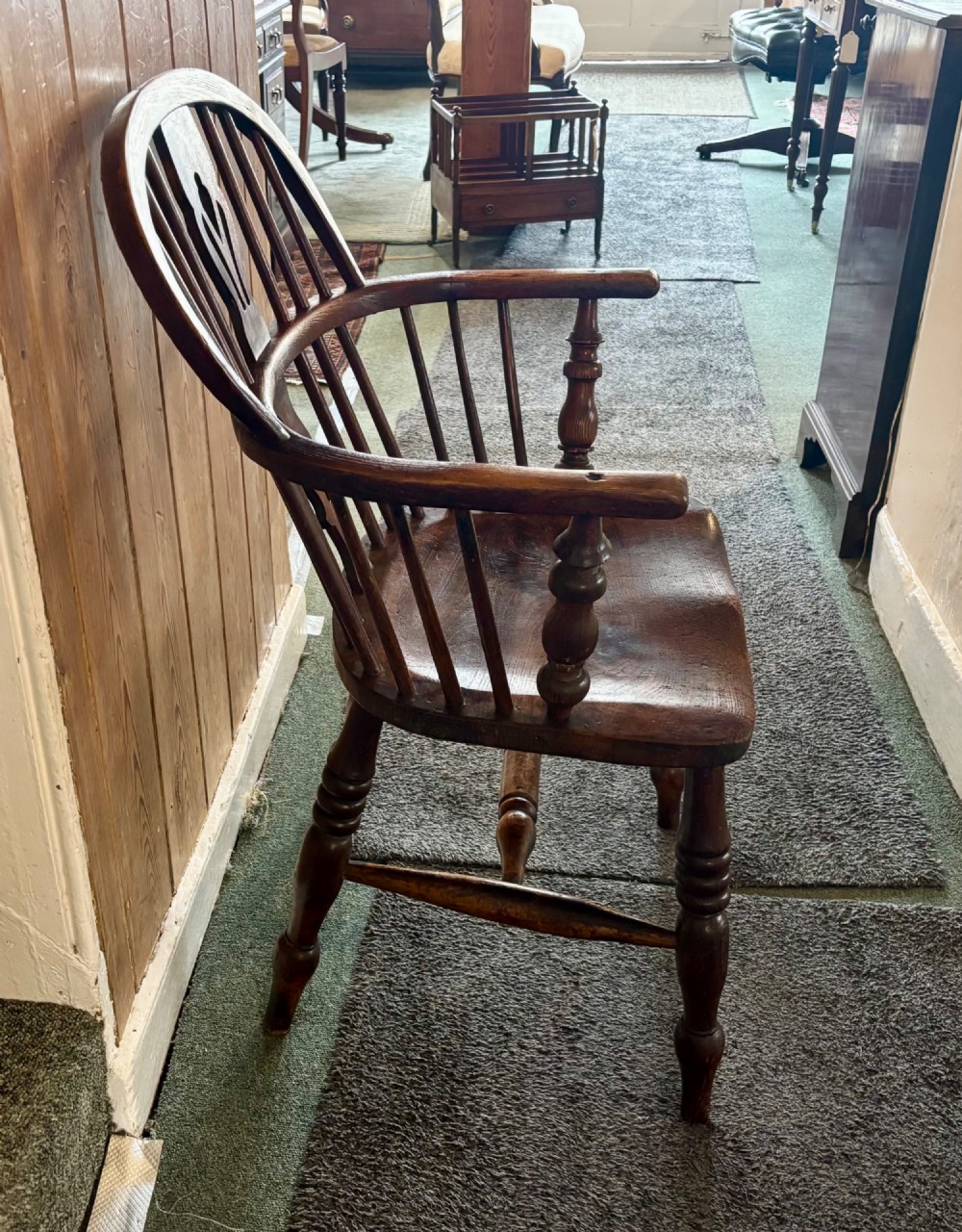 A 19th-century dark elm Windsor armchair featuring a curved hoop back, central pierced splat, turned spindles, curved armrests, shaped seat, and turned legs joined by stretchers. View IV