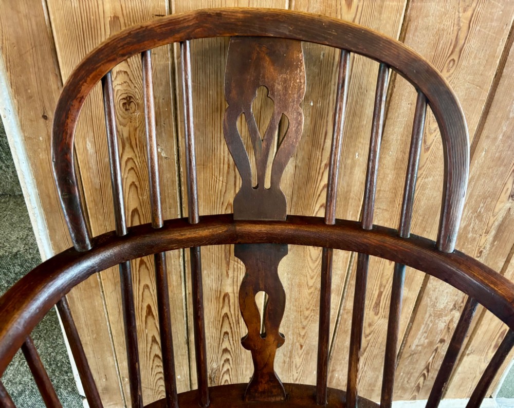 A 19th-century dark elm Windsor armchair featuring a curved hoop back, central pierced splat, turned spindles, curved armrests, shaped seat, and turned legs joined by stretchers. View V